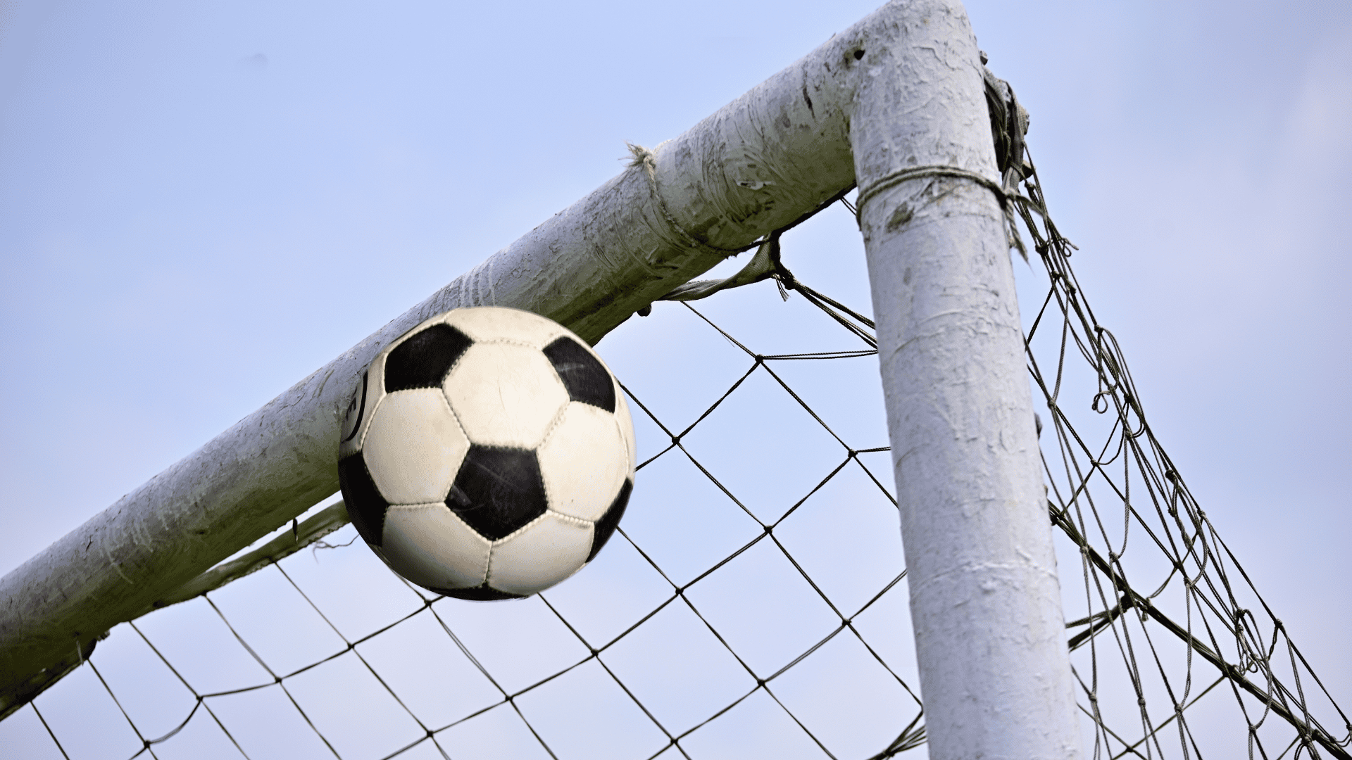 soccer ball fully crossing the goal line as a goalkeeper dives and the referee signals a goal
