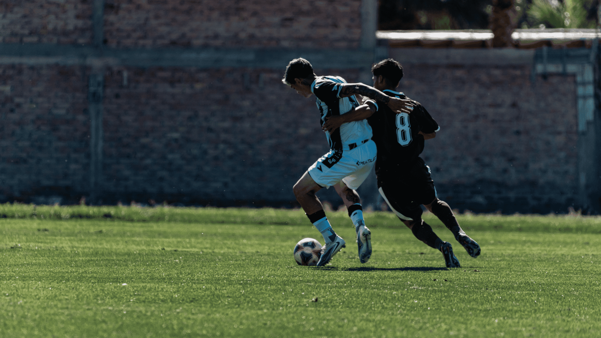 soccer player being pulled by an opponent while controlling the ball during a physical challenge on the field