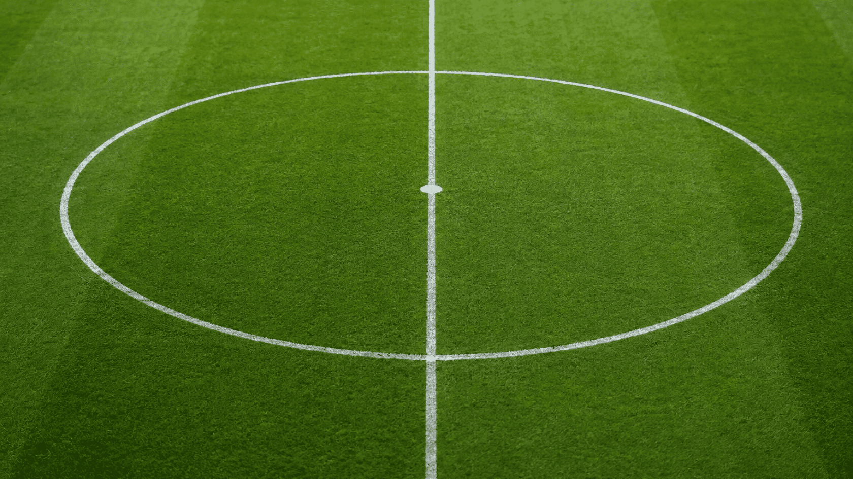the center circle halfway line and center mark are clearly outlined in white on the green soccer field