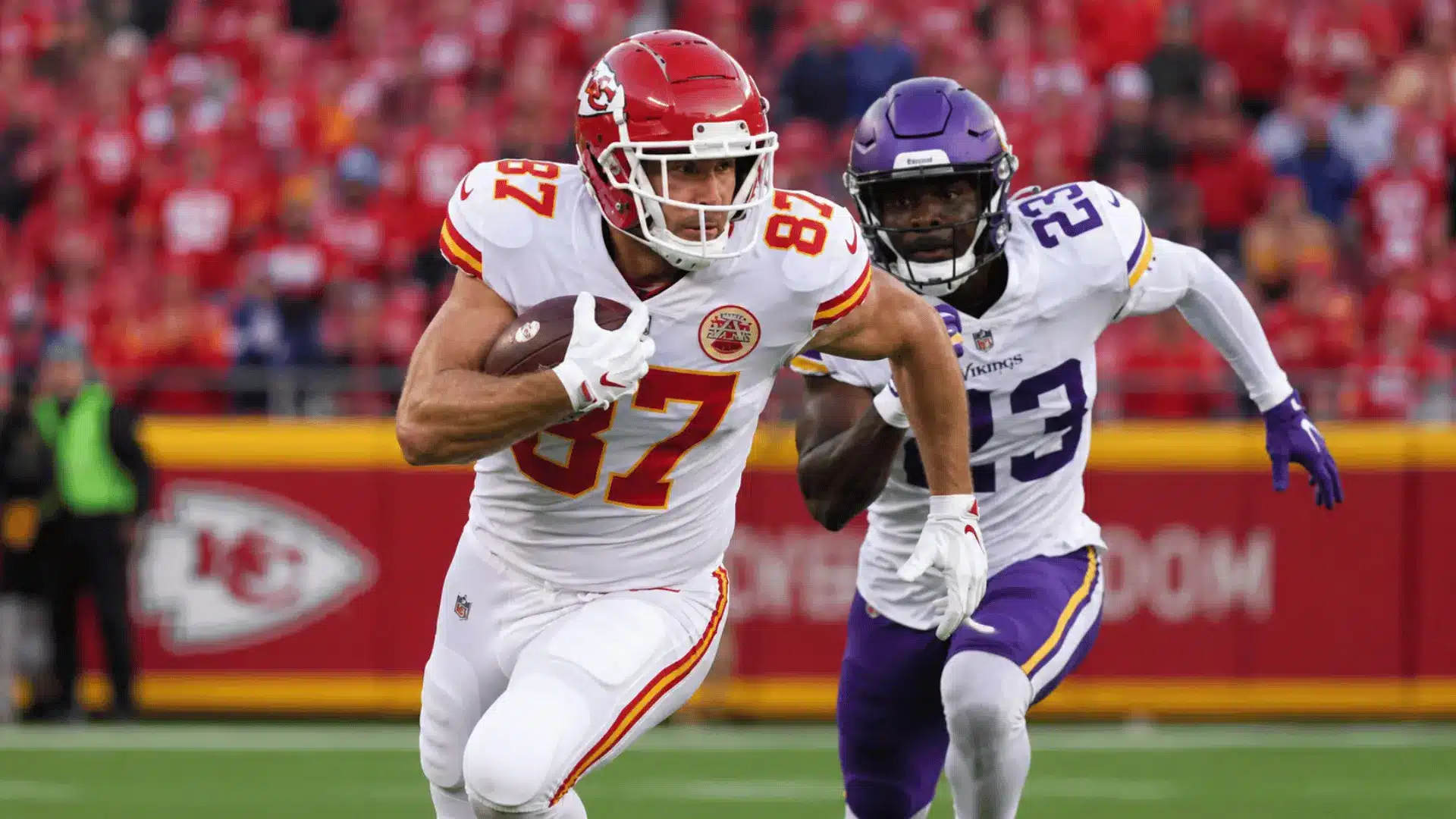 tight end running with the football while defenders chase during a live game in a crowded stadium
