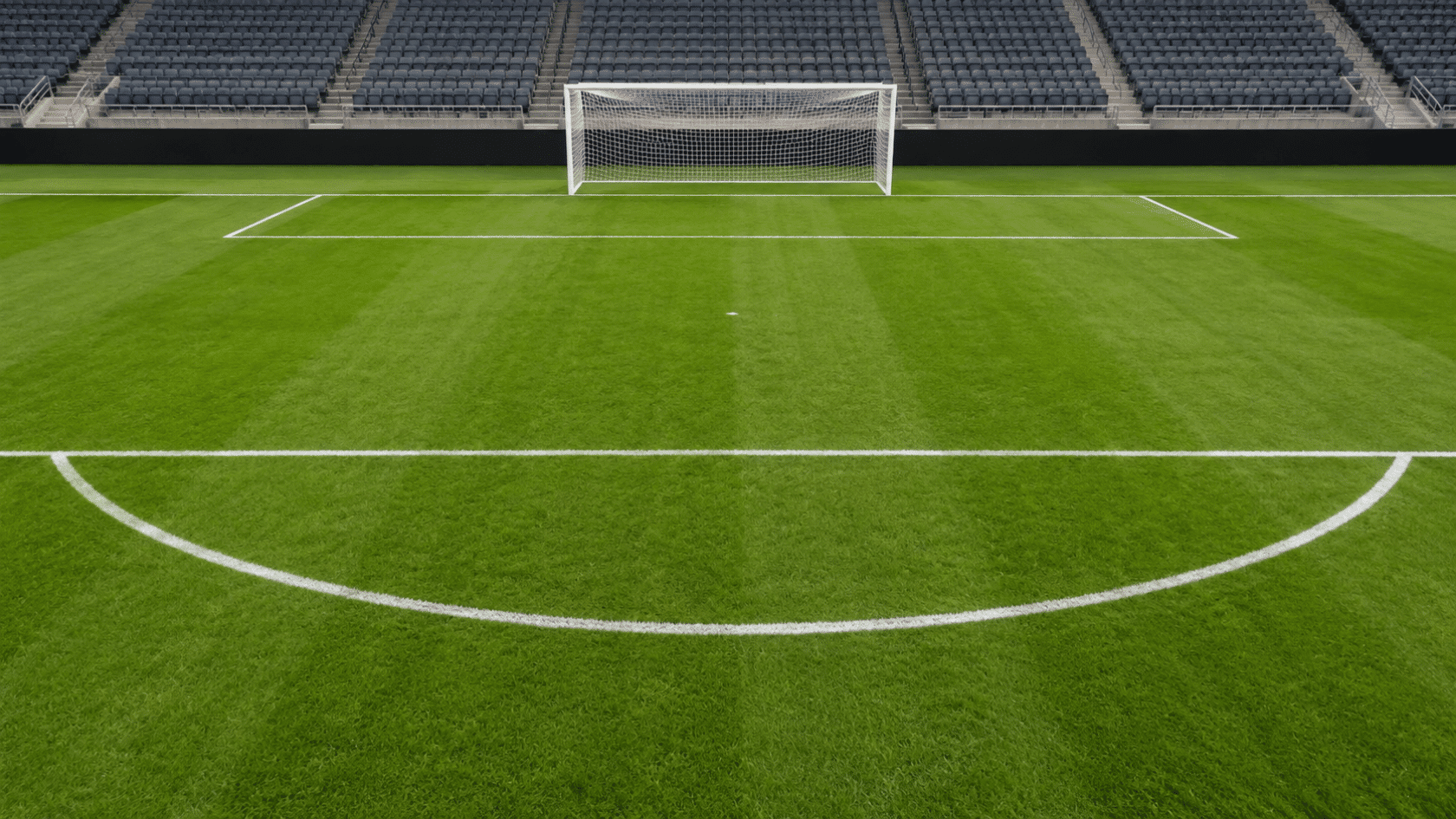 wide view of a green soccer field showing the goal post penalty area and penalty arc clear white field markings