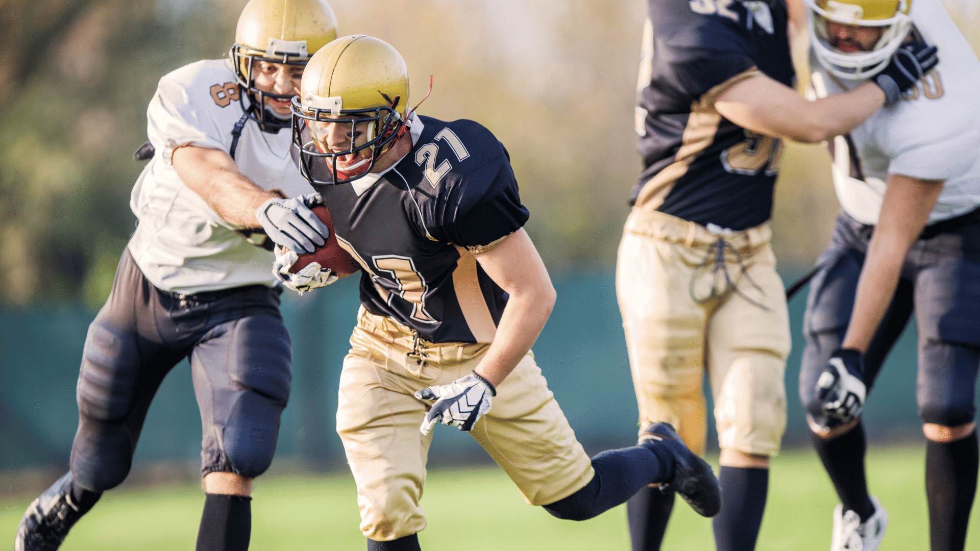 young college football player carrying the ball while defenders close in during a game on the field