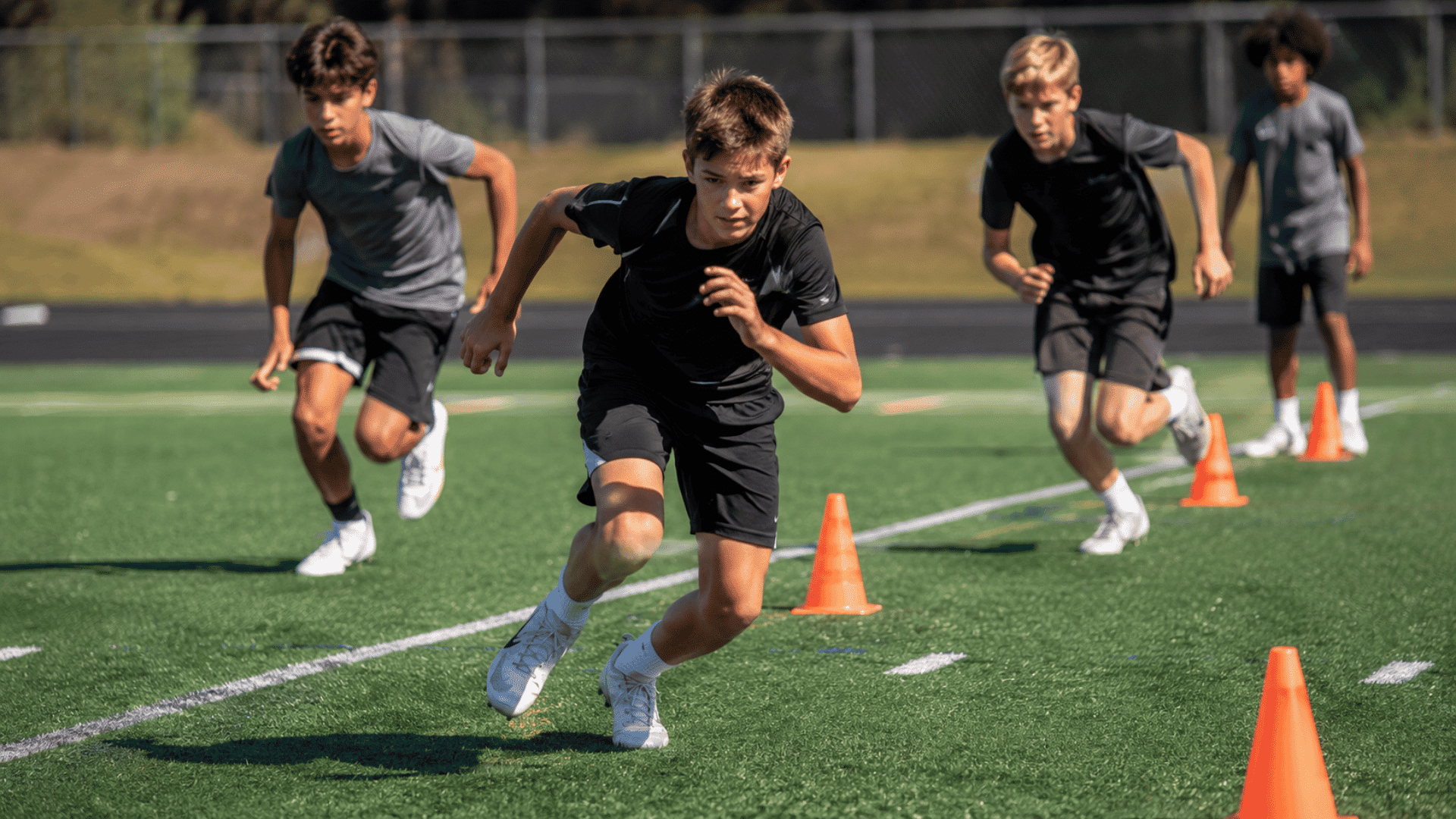 young football players running shorter cone to cone sprints during a youth conditioning drill