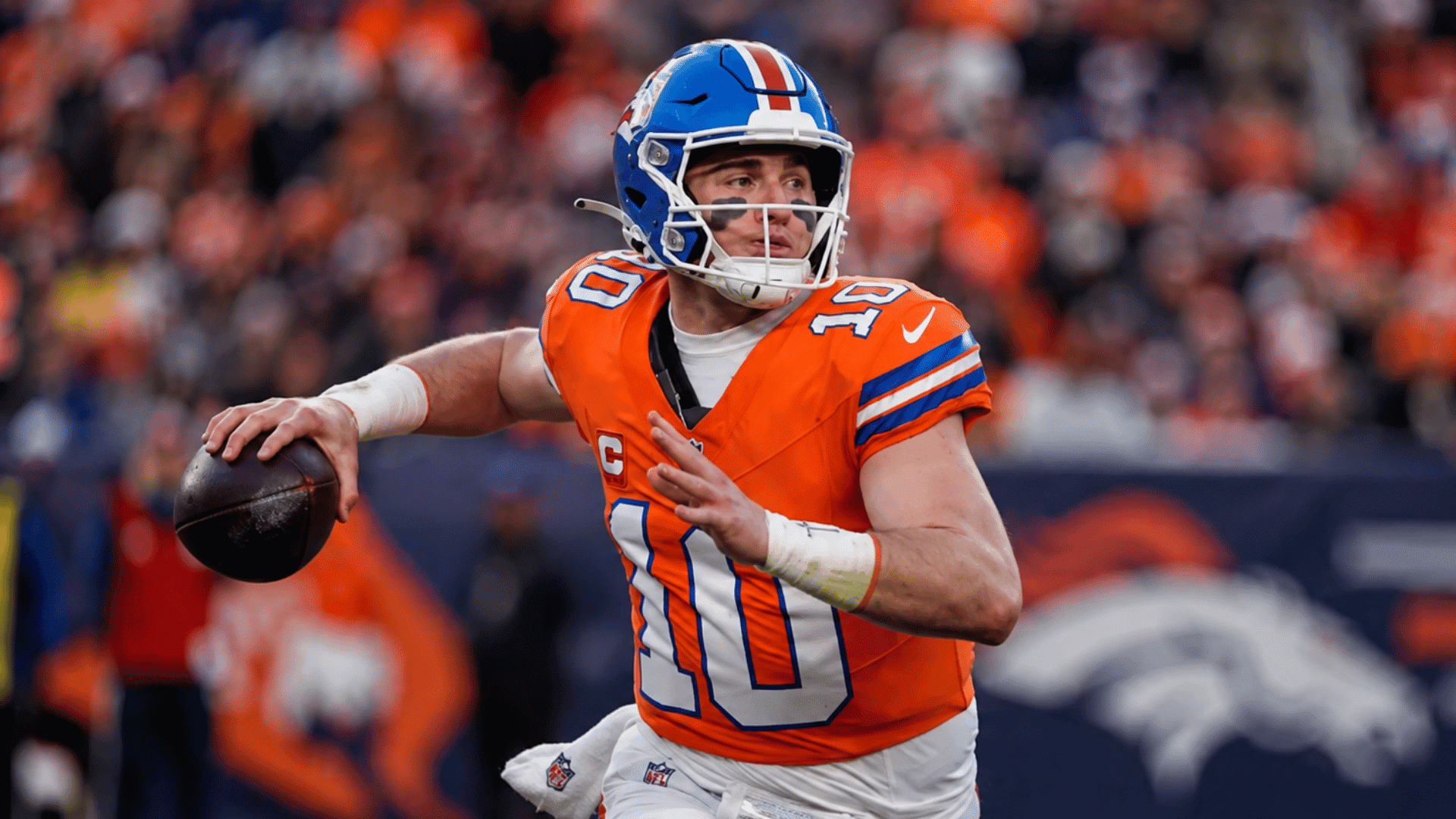 broncos quarterback prepares to throw the football during a game with fans blurred behind him