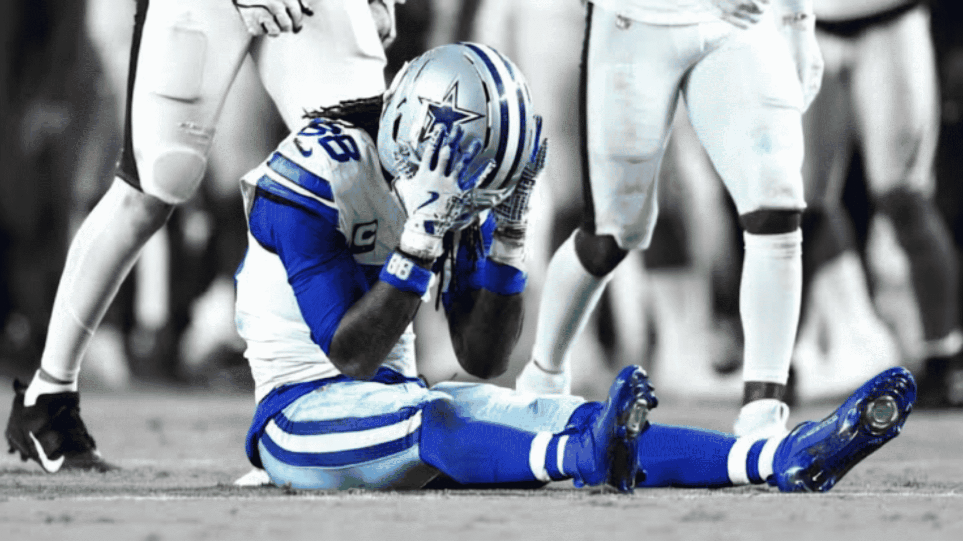 dallas cowboys player ceedee lamb sitting on the turf with his hands on his helmet