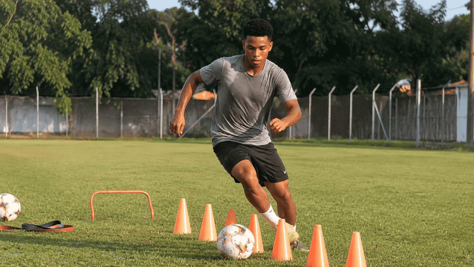young college soccer player dribbling through orange cones during a sweaty agility training drill