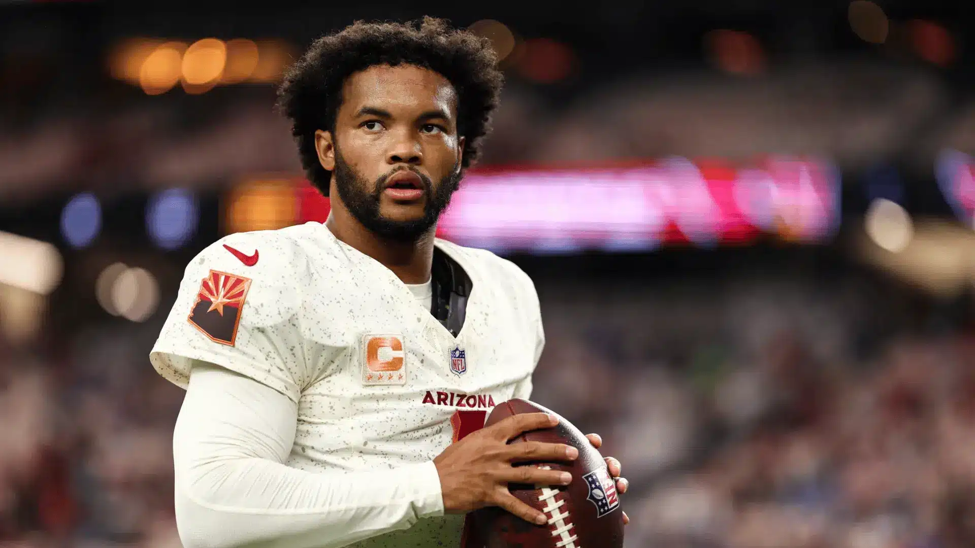 arizona quarterback in white uniform holding a football and looking downfield during a game