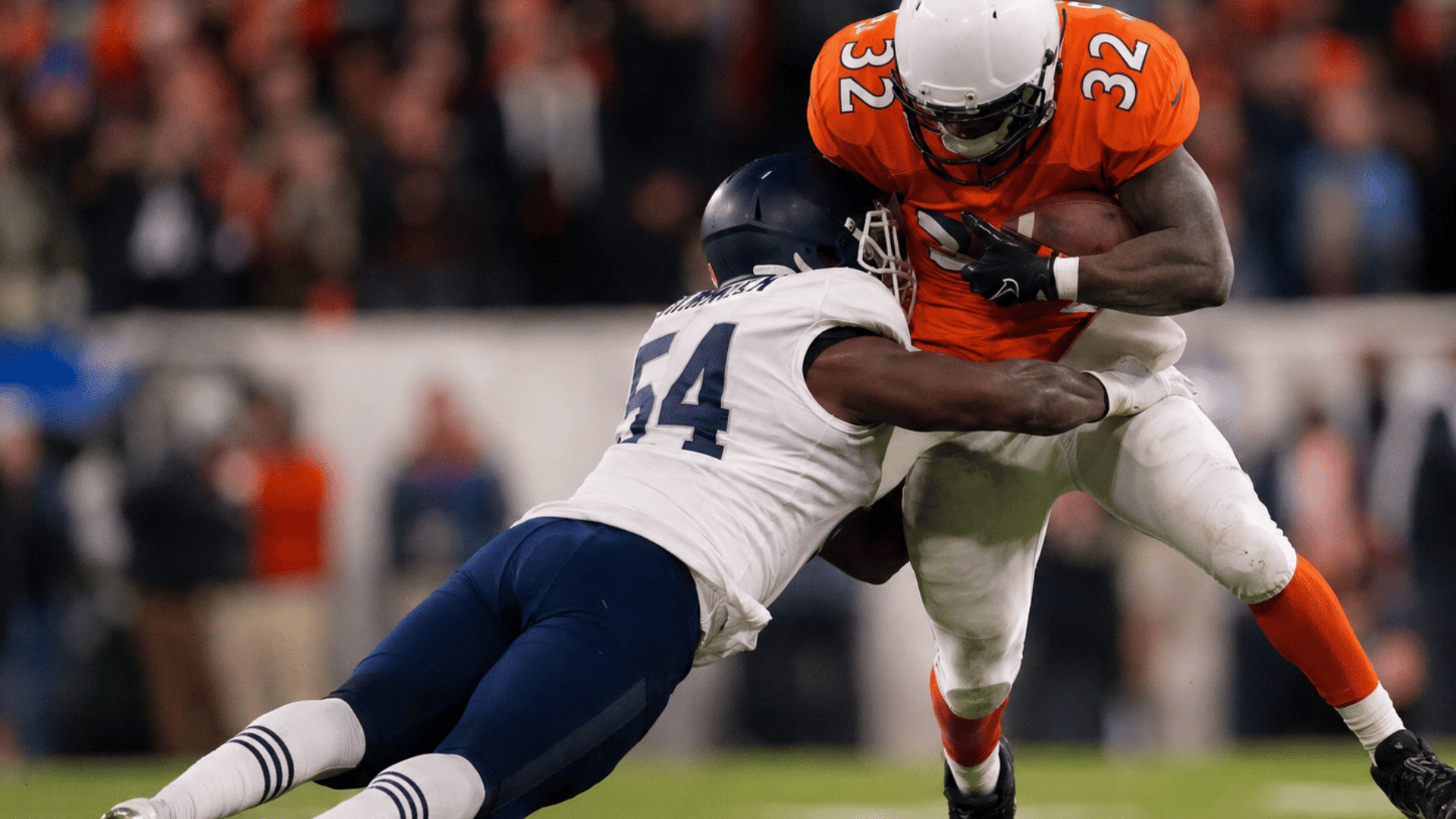 cornerback in white jersey tackles an orange jersey ball carrier during an american football game