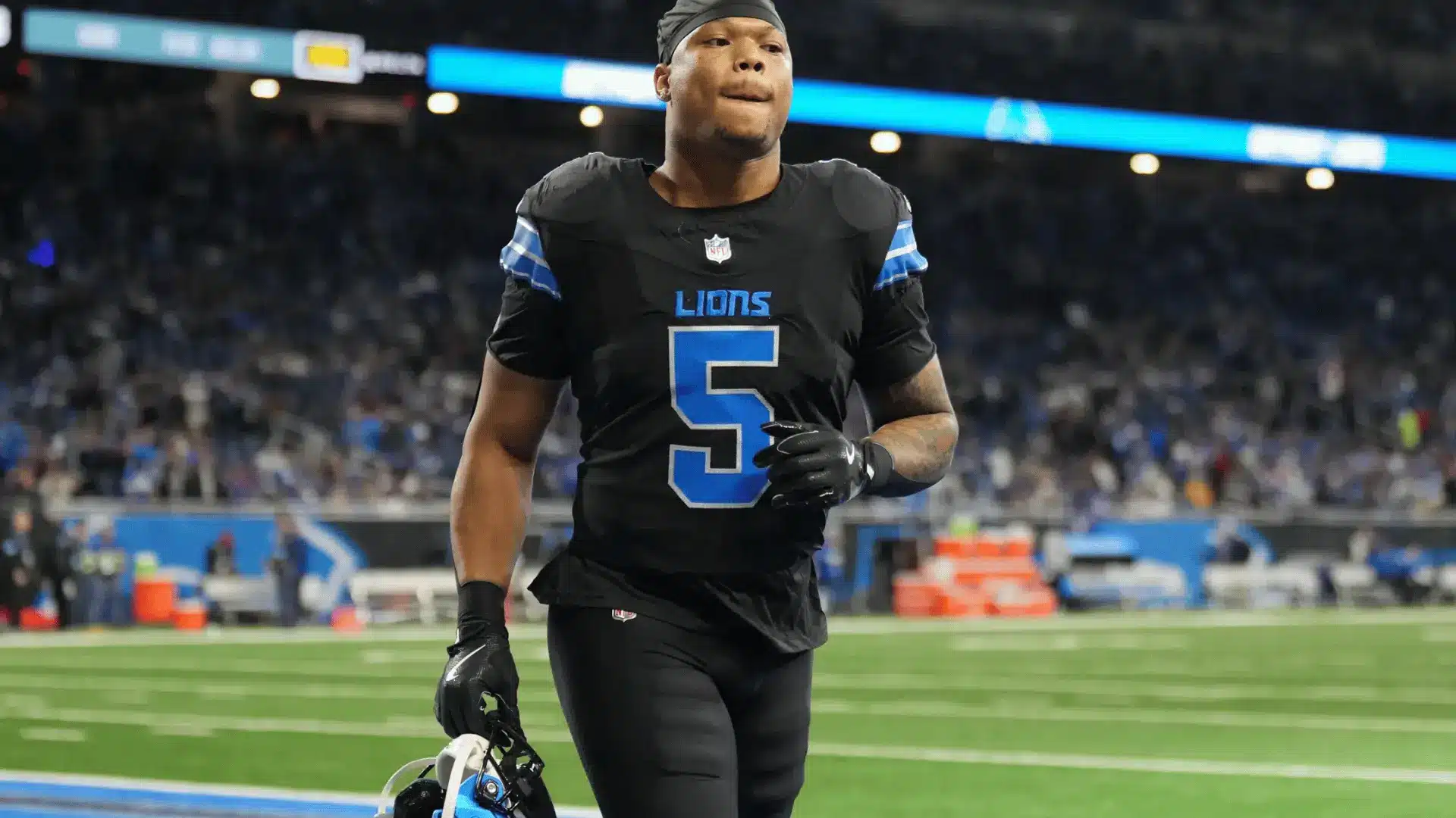 detroit football player in black number five uniform walking across the field after a game