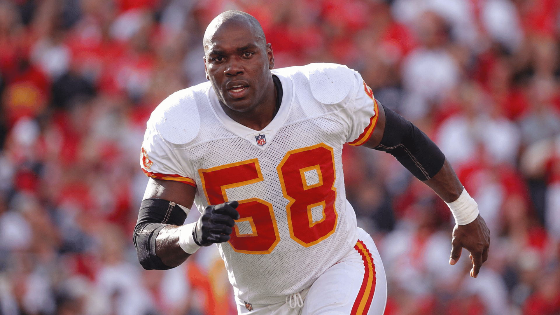 derrick thomas charging forward in a white kansas city chiefs uniform during game action on the field