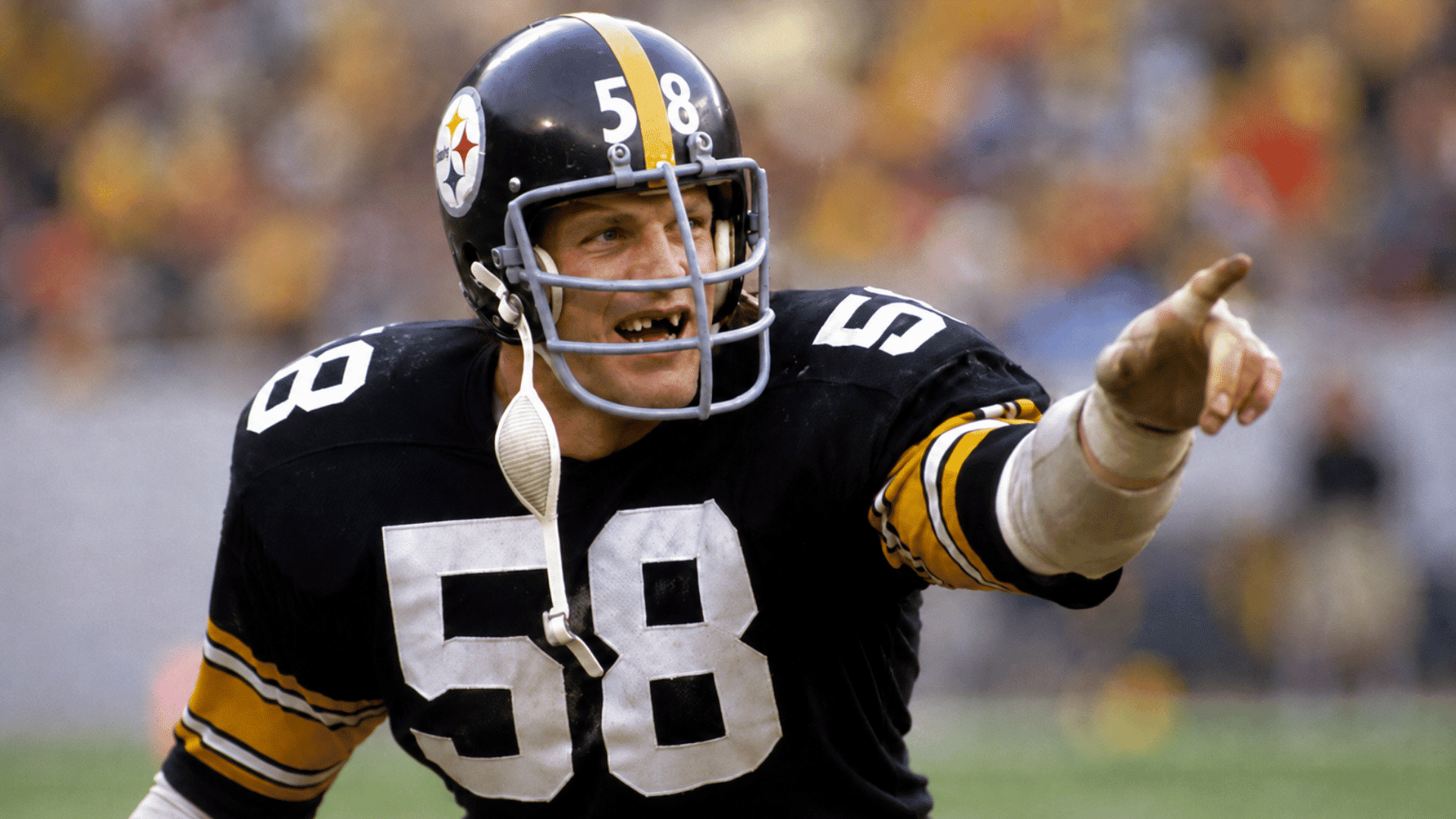 jack lambert pointing across the field in a black pittsburgh steelers uniform during game action