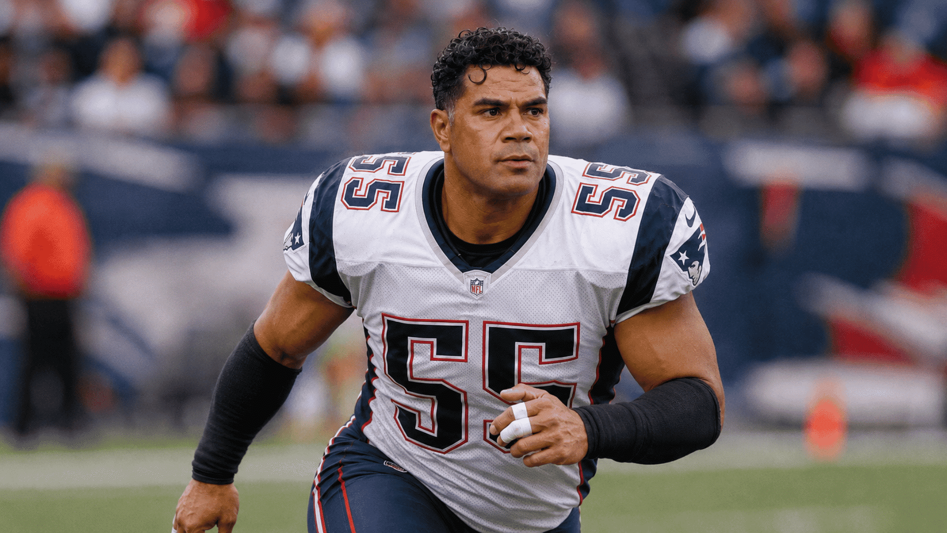 junior seau running forward in a white new england patriots jersey during game action on the field