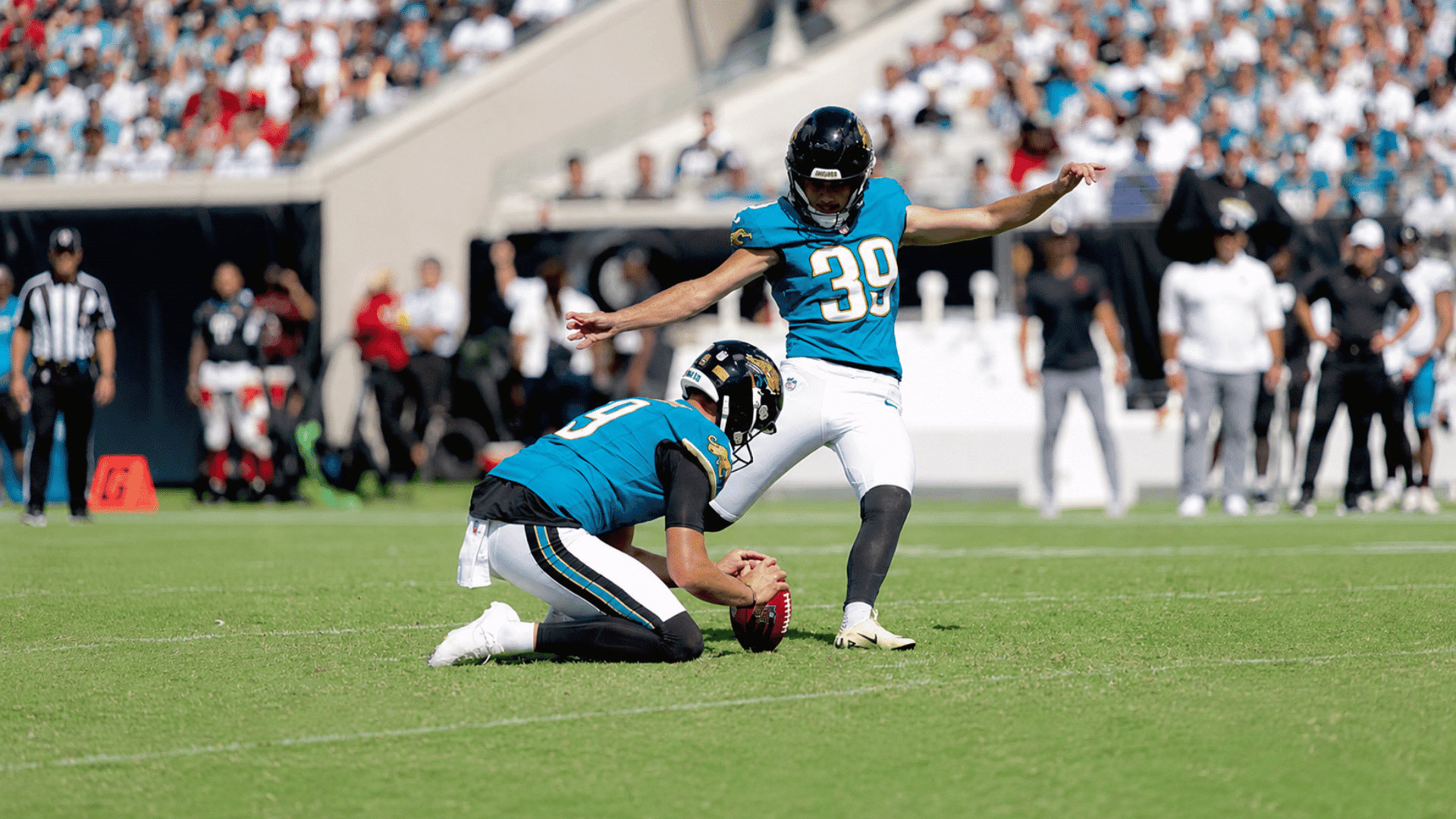 Jacksonville Jaguars kicker attempts a field goal as holder steadies the football on field