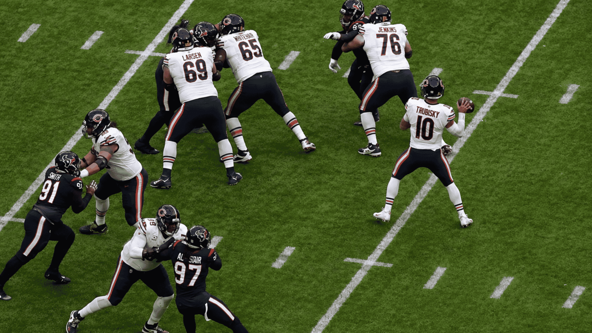 quarterback preparing to throw from the pocket while offensive linemen block multiple rushing defenders