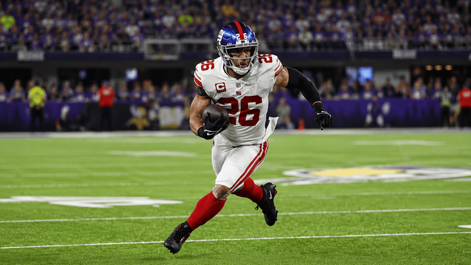 football player in white and red uniform running with the ball across a stadium field