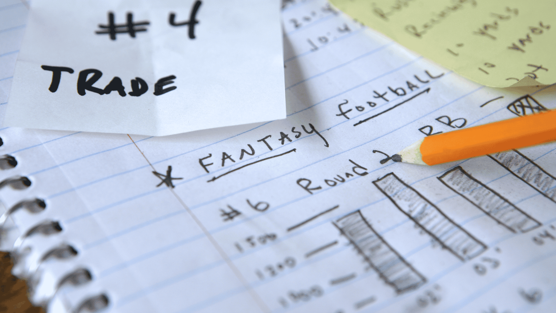 fantasy football trade notes with player rankings round values and a pencil on a notebook
