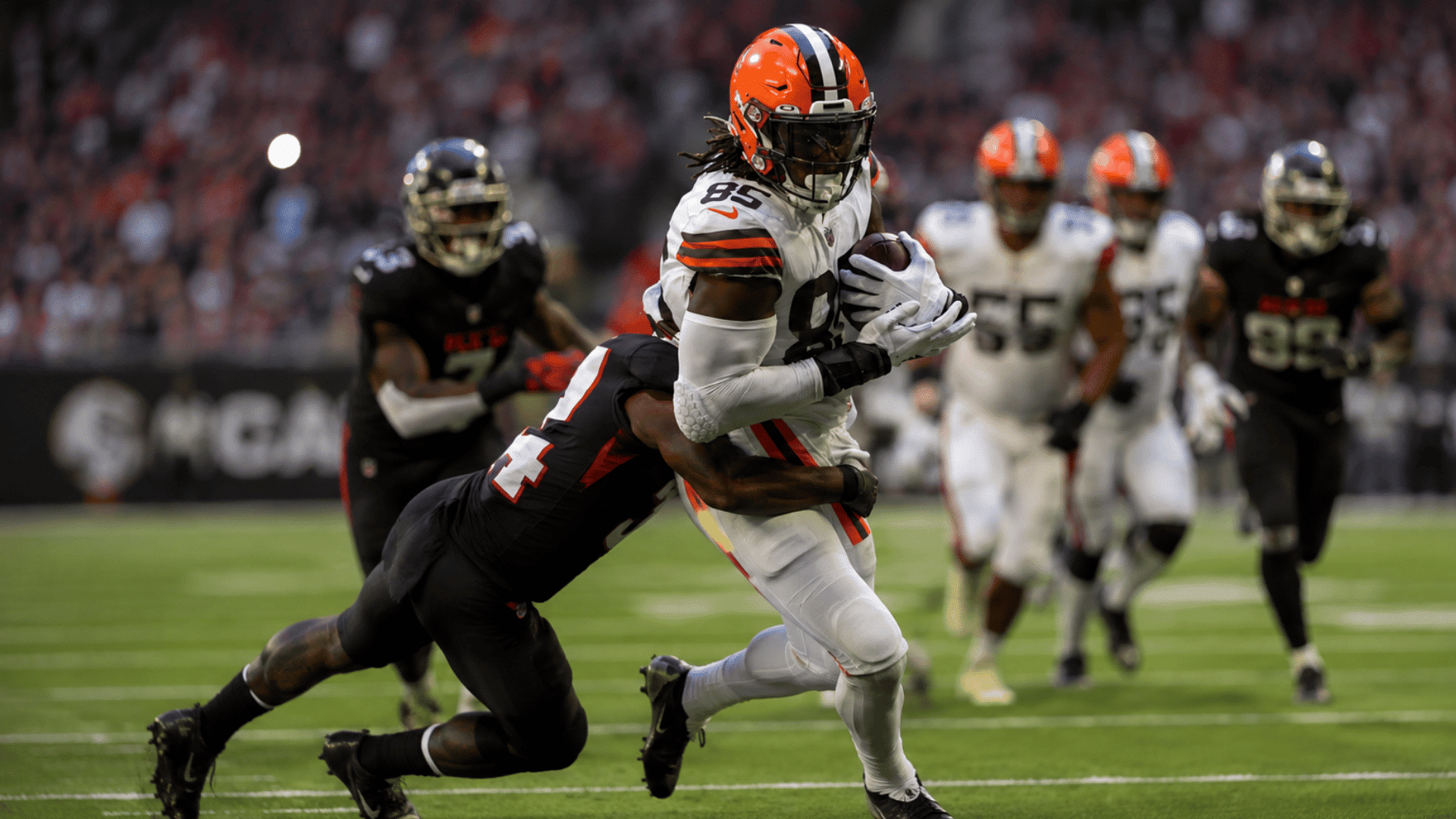 football player in white uniform carrying the ball as a defender tackles him during game