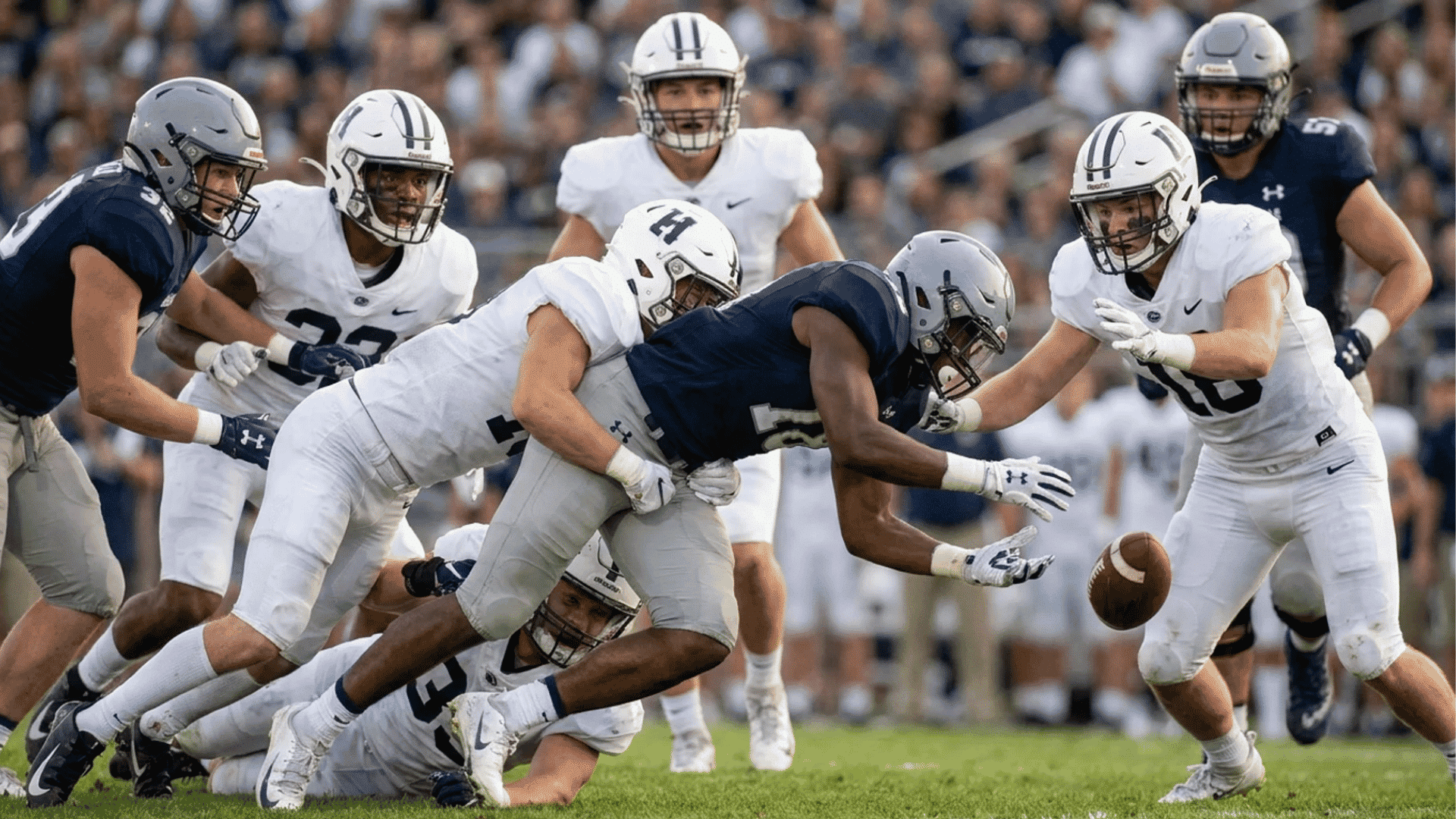 football player loses control of the ball during a tackle as nearby players react to the fumble