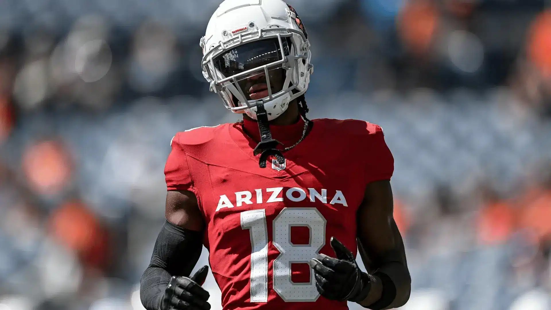 arizona football player in red number eighteen uniform wearing a helmet and gloves on field