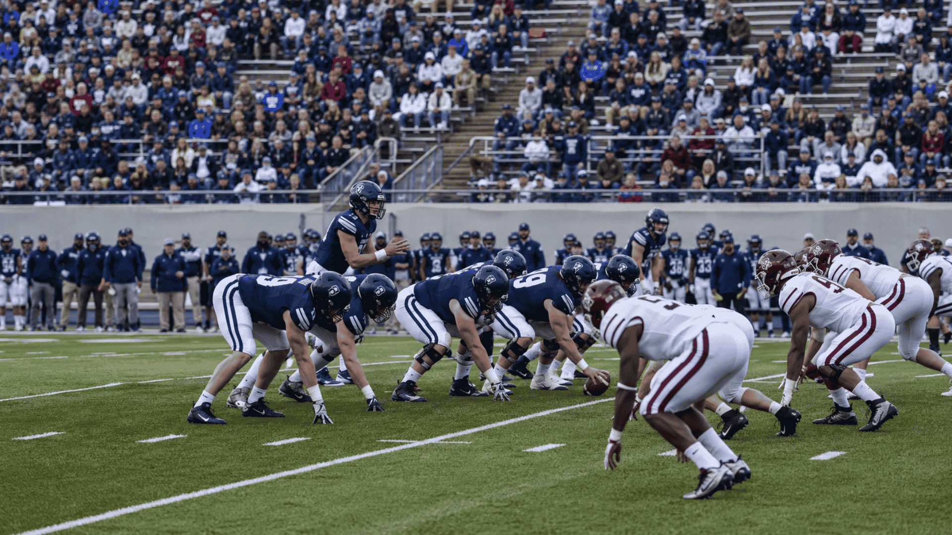 college football offense lines up at the line of scrimmage against a defense before the snap