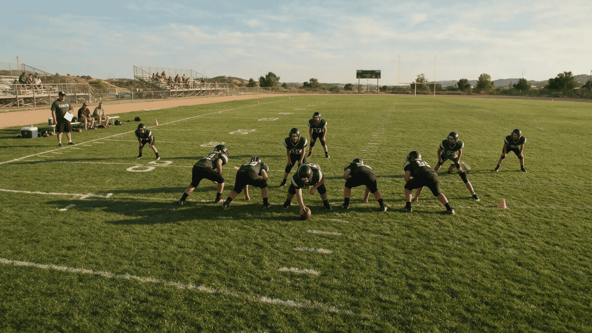 youth football players lined up in a wing t offense during a supervised practice on a grass field