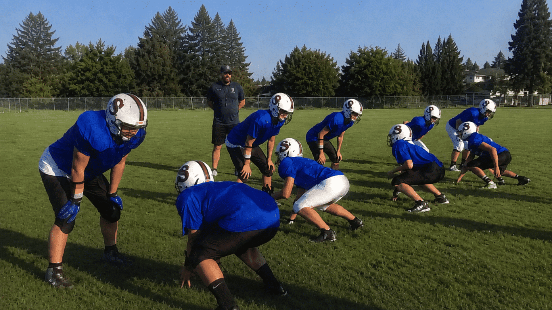 youth football players practicing wing-t blocking handoffs and footwork on a grass field